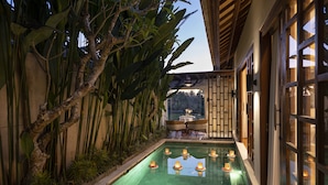 Una piscina con velas, rodeada de plantas y una terraza de madera.