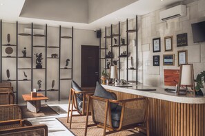 Un área de recepción moderna con mostrador, asientos y estanterías de pared con objetos decorativos.