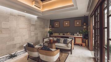 A modern living room with a stone wall, a dining area with a kitchen in the background, and large windows.