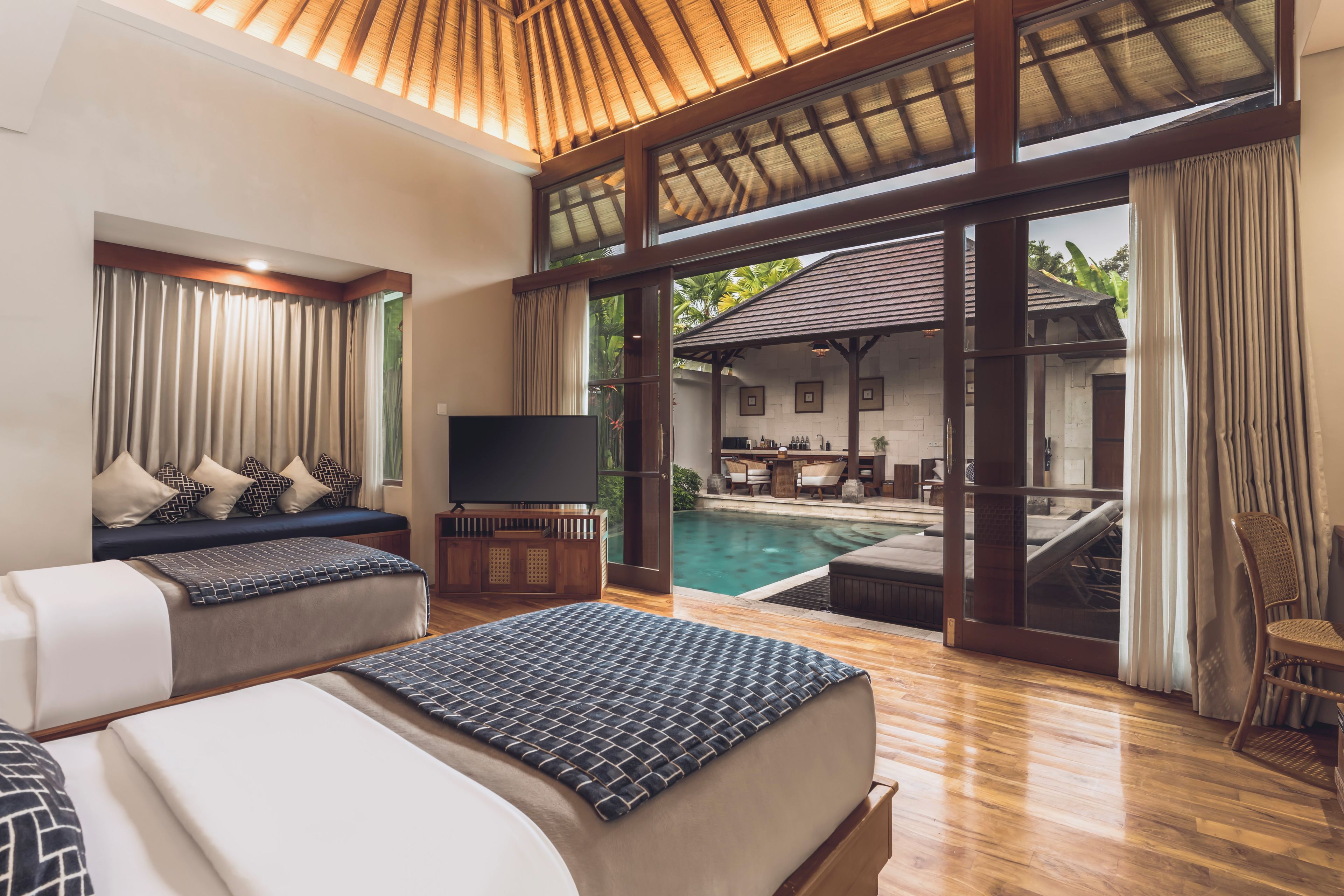 A hotel room with a large bed, a TV, a pool, and a dining area.