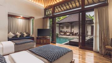 A hotel room with a large bed, a TV, a pool, and a dining area.