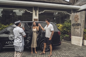 Um SUV preto estacionado em frente a um edifício com uma placa que diz 'ASVARA UBUD VILLA'.