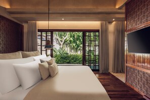 Une chambre d’hôtel avec un grand lit, une télévision et une vue sur la verdure par la fenêtre.