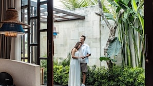 Una habitación de hotel moderna con una cama grande, una piscina pequeña y vistas a un jardín exuberante.