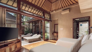 Una habitación amplia con un televisor grande, dos camas, techo de madera y vistas al exterior.