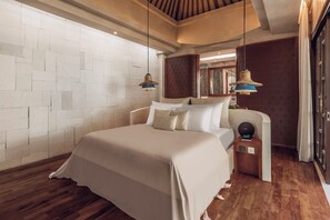 A modern bedroom with a large bed, wooden flooring, a white brick wall, and a wooden ceiling. - Asvara Villa Ubud by Ini Vie Hospitality (Ubud)