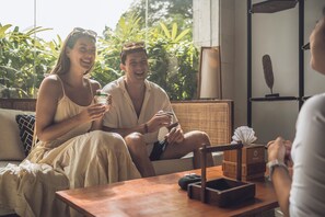 Una habitación con un sofá, una mesa con una caja y una vela, y una lámpara.