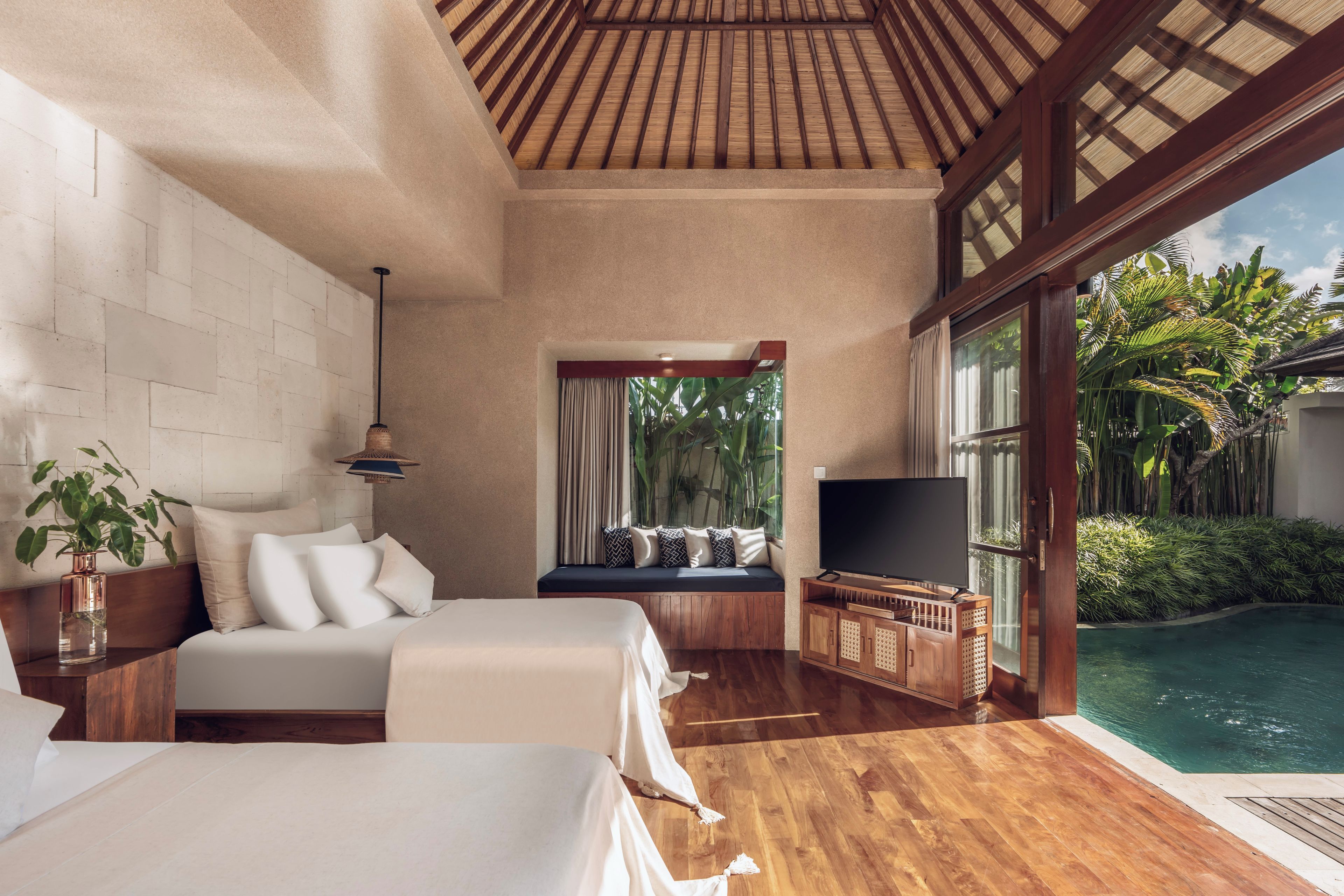 A bedroom with a large bed, a TV, and a view of a swimming pool.