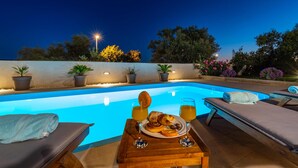 A poolside area with lounge chairs, a table with food and drinks, and potted plants. - Nice home in Posedarje with sauna (Posedarje)