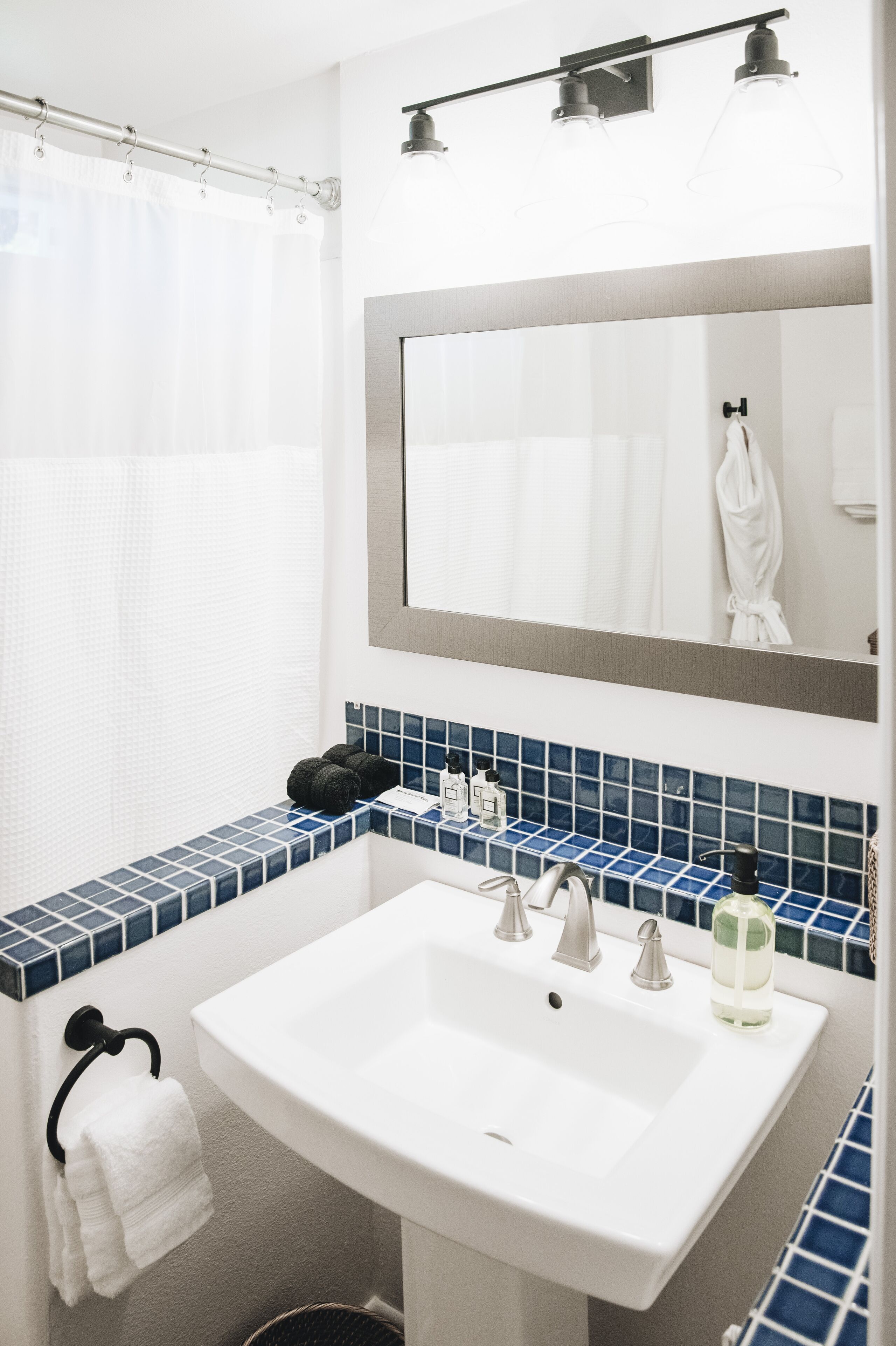 A bathroom with a white sink, blue-tiled countertop, and a mirror above the sink.