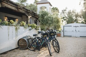 Un camino de grava con dos bicicletas estacionadas cerca de un edificio blanco de techo inclinado y una pequeña torre con campana.