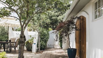 Stroll along the paved pathway to a serene outdoor space with a charming seating area and lush greenery.