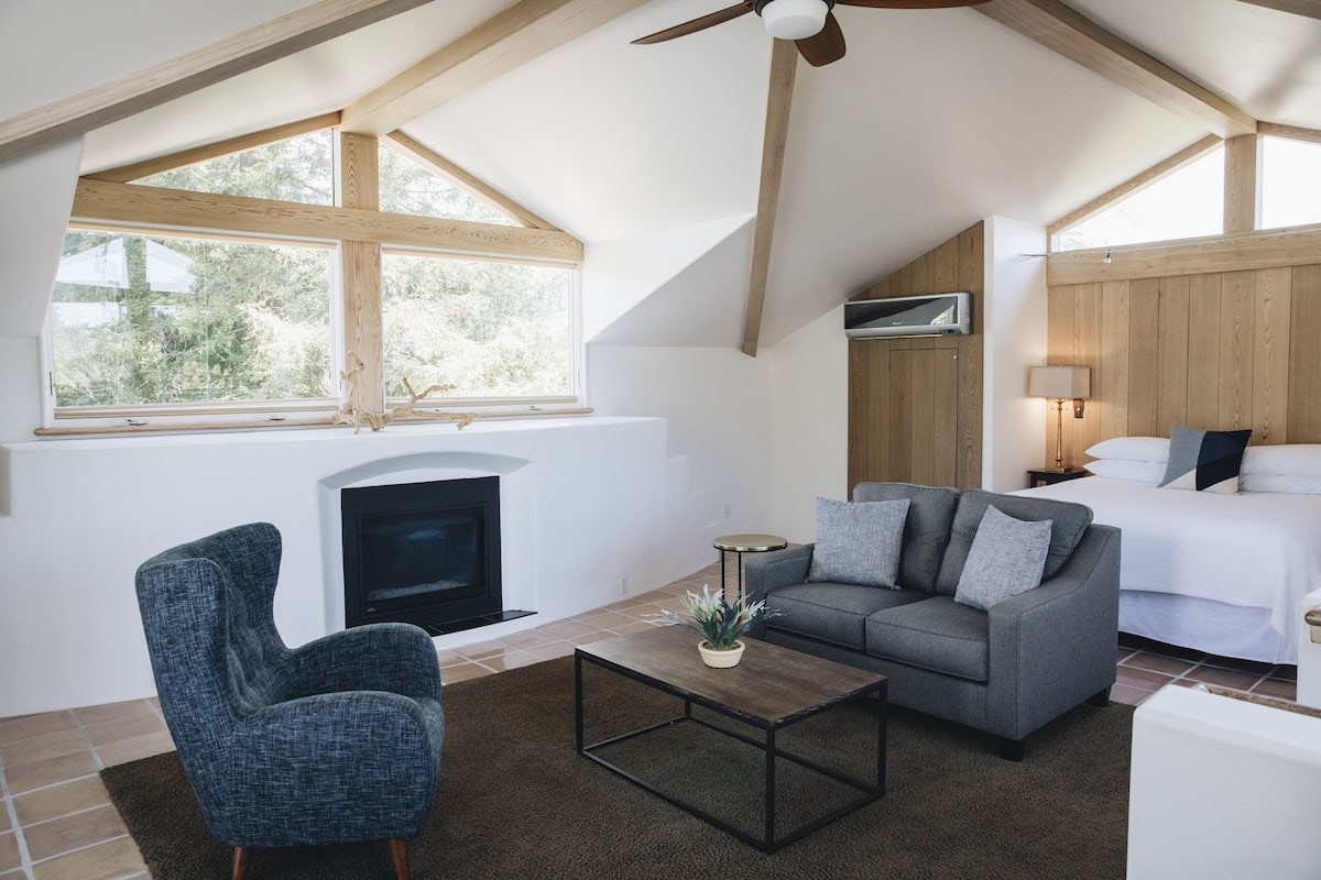 A cozy room with a fireplace, a sofa, a coffee table, and a bed.