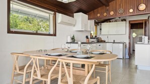 A modern kitchen with white cabinets, a dining area with a wooden table and chairs, and a view of greenery through a window. - Beautiful home in Vordingborg with WiFi (Vordingborg)