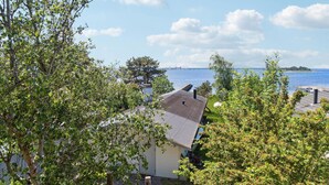 A house with a sloped roof, surrounded by lush greenery and a view of a body of water with a bridge in the distance. - Beautiful home in Vordingborg with WiFi (Vordingborg)