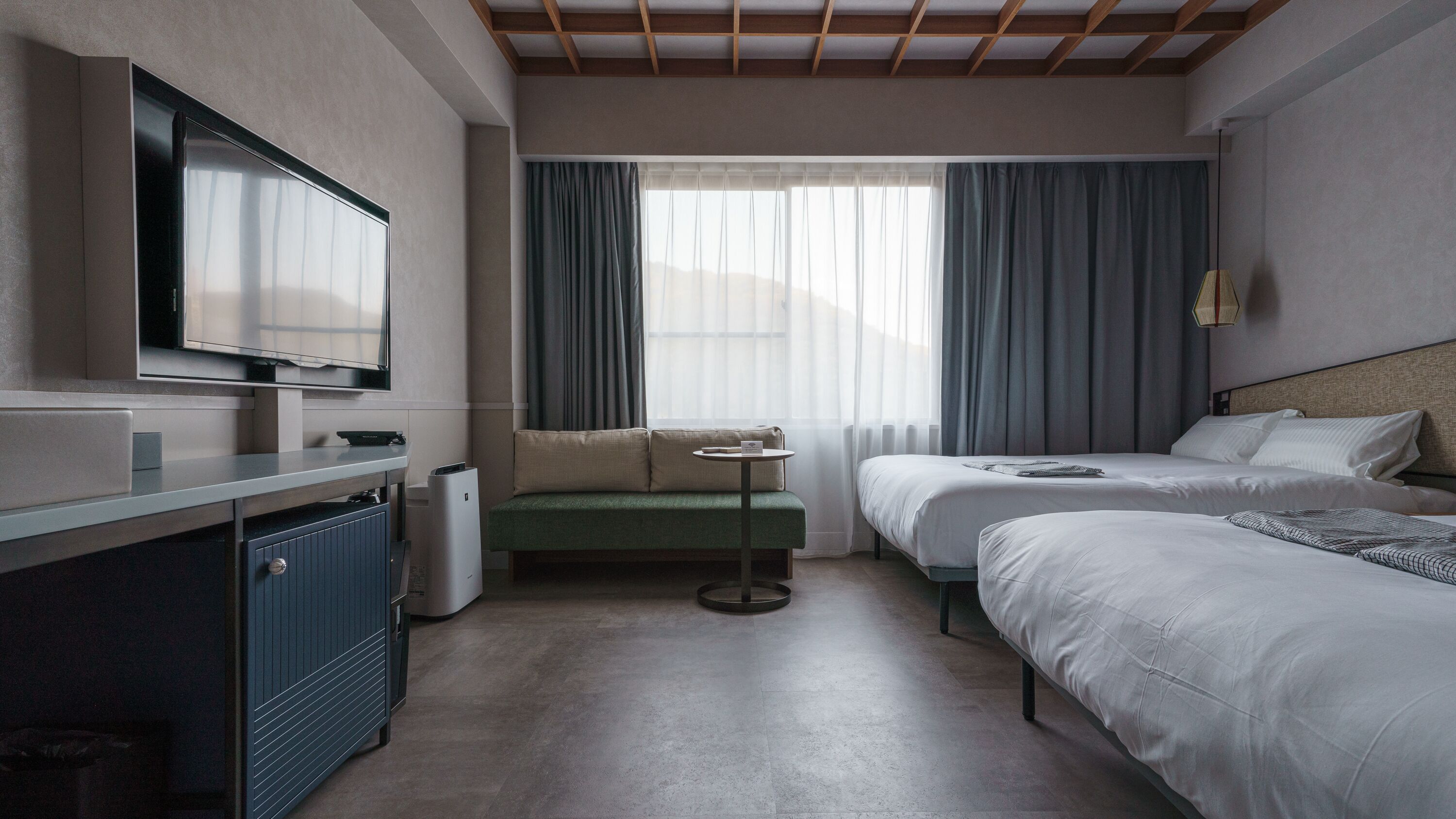 Una camera d'albergo con un letto, un divano, una TV e un tavolino.