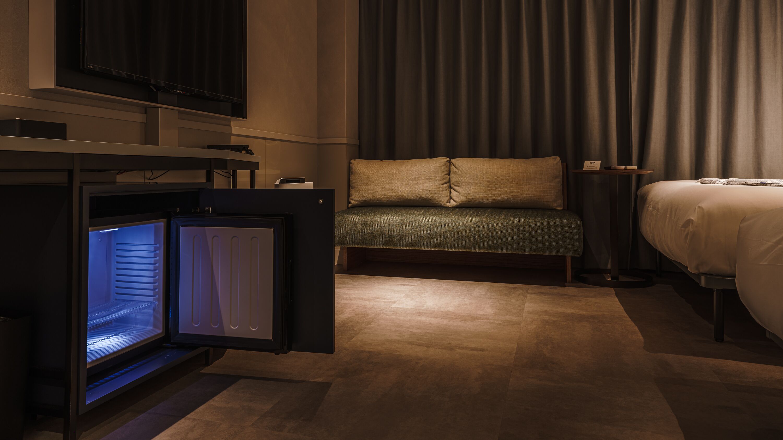 Ein Hotelzimmer mit Bett, einer Sitzecke, einem Fernseher und einer Minibar.