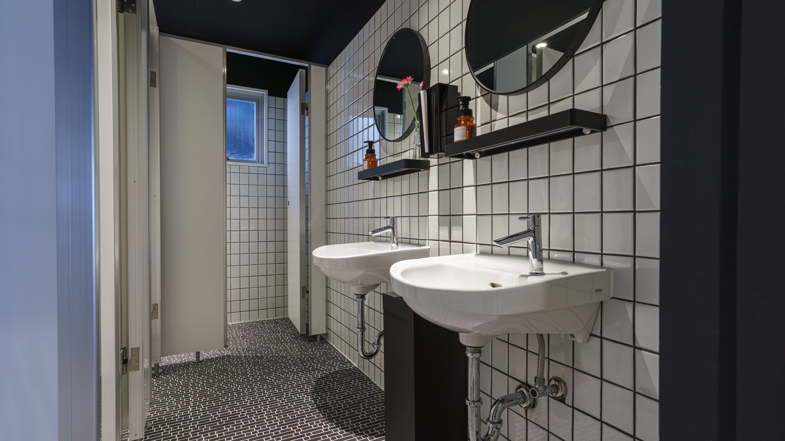 Een moderne badkamer met twee wastafels, een spiegel en een raam.