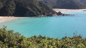 A coastal landscape with a beach, clear turquoise waters, and lush green hills in the background. - Hotel Aoka Kamigoto (Shinkamigoto)