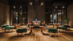 A modern interior with a brick wall, a fireplace, and green upholstered chairs. - Hotel Aoka Kamigoto (Shinkamigoto)