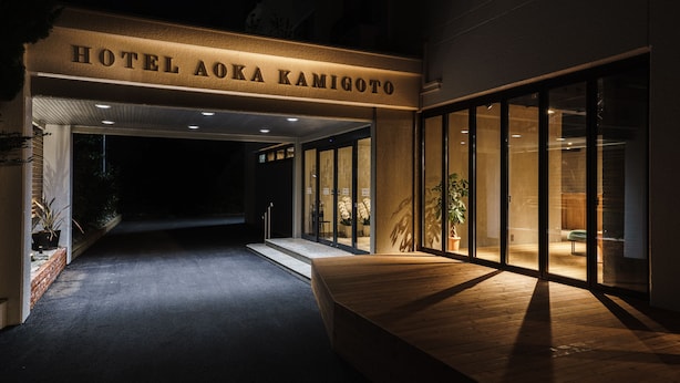 The entrance of Hotel Aoka Kamigoto with a wooden bench outside and glass doors leading inside. - Hotel Aoka Kamigoto (Shinkamigoto)