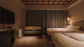 Ett hotellrum med en soffa, två sängar, en TV och ett litet bord.