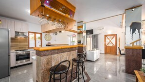 Une cuisine moderne dotée de plans de travail en granit, d’appareils électroménagers en acier inoxydable et d’un coin bar en bois avec des tabourets.