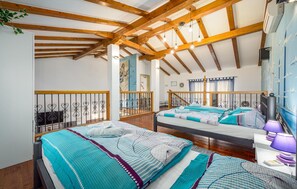 Ein Schlafzimmer mit zwei Betten, Holzbalken, einem Balkon und einem Wandgemälde.