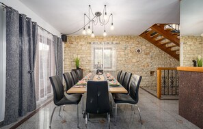 Ein Essbereich mit Steinwand, einer Holztreppe und einem Chandelier.