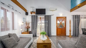 Un salon avec deux canapés gris, une table basse en bois et une porte dotée d’un panneau de verre.