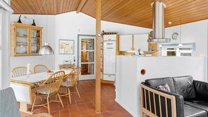 Una cocina compacta con armarios blancos, horno integrado y campana extractora de acero inoxidable.
