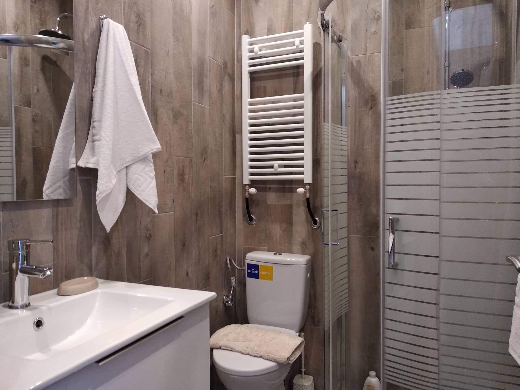 Een badkamer met een wit wastafel, toilet en douche.