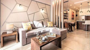 A modern living room with a sofa, coffee table, and a dining area with a kitchen in the background. - Thessaloniki Historic Center - Metro Apartment (Thessaloniki)