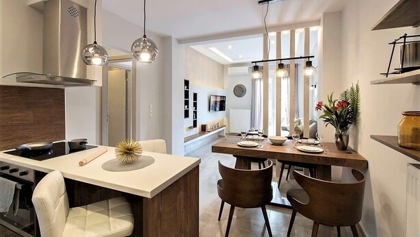 A modern kitchen with a central island, pendant lighting, and a dining area with chairs. - Thessaloniki Historic Center - Metro Apartment (Thessaloniki)