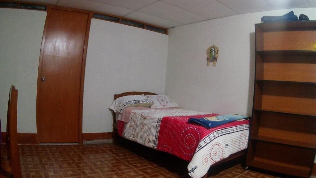 Un dormitorio con cama, armario y estantería.