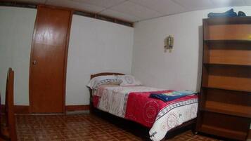 Un dormitorio con cama, armario y estantería.