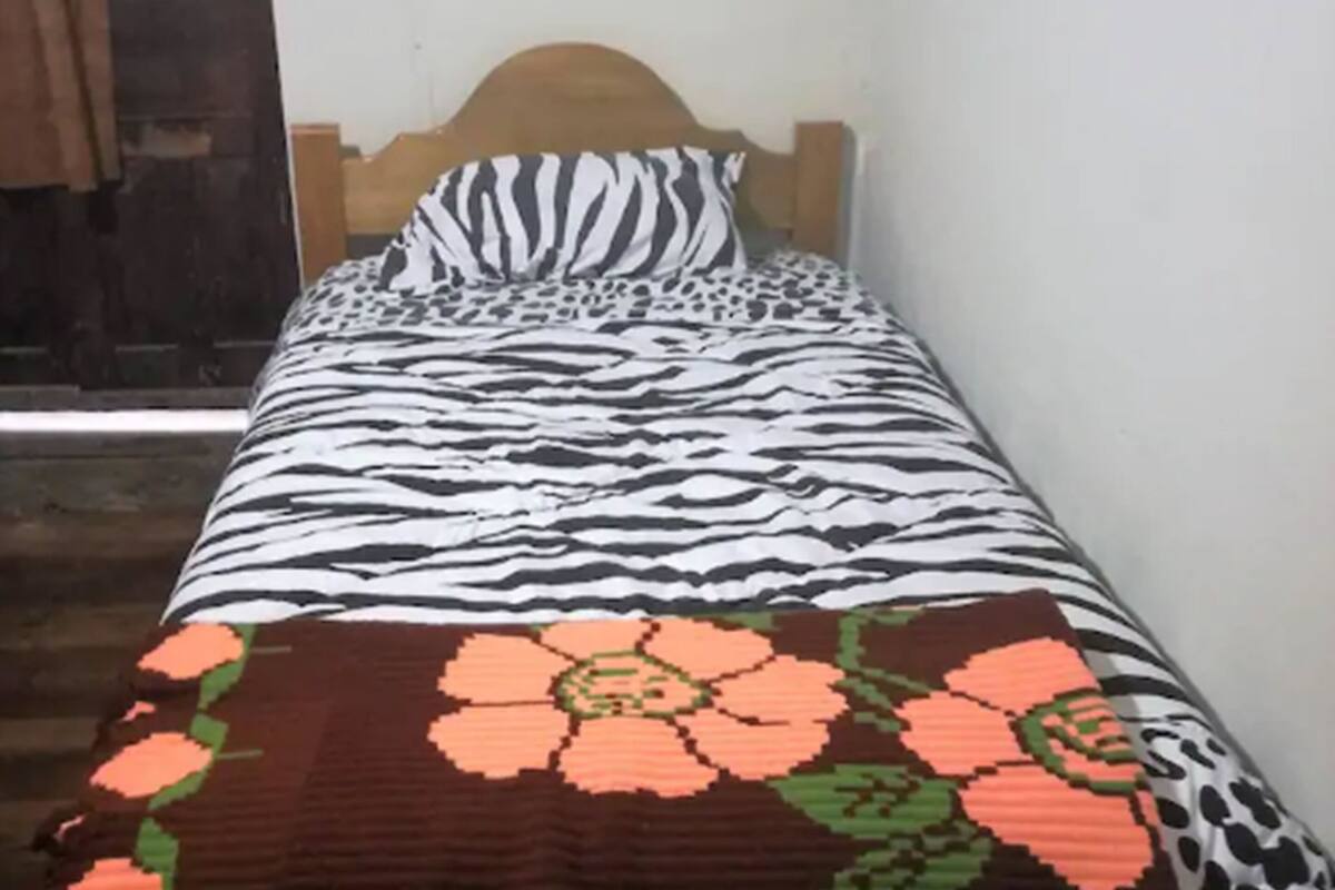 A single bed with a zebra-patterned bedspread and a floral blanket.