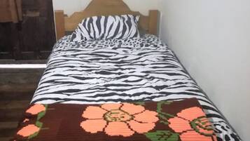 A single bed with a zebra-patterned bedspread and a floral blanket.