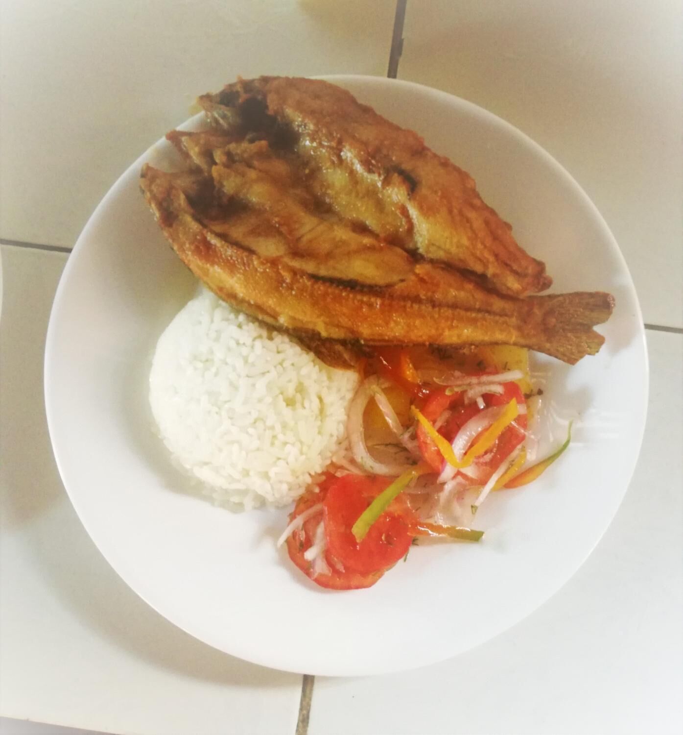 A plate with fried fish, white rice, and a vegetable salad.