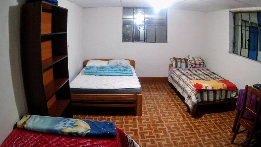 Ein Zimmer mit zwei Betten, einem Holzregal und einem Fenster.