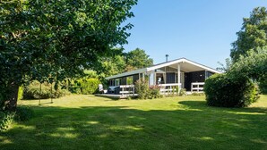 A two-story house with a covered patio and a lawn. - Cozy home in Nysted with house sea view (Nysted)