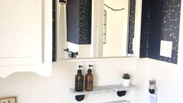 A bathroom with a white sink, black and white tiled walls, a mirror, and a ceiling light fixture.