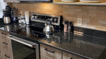 A kitchen with a stainless steel microwave, a kettle, a coffee maker, and a built-in oven.