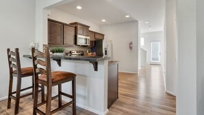 Una cocina moderna con armarios de madera oscura, un microondas integrado y un refrigerador de acero inoxidable.