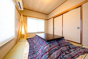 Um quarto japonês tradicional com tatames, futon, portas corrediças shoji e uma escada para armazenamento.
