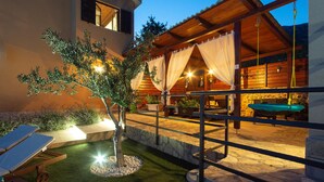 A well-lit outdoor area with a pool, lounge chairs, and a wooden pergola. - Amazing home in Kastel Sucurac (Kastel Sucurac)