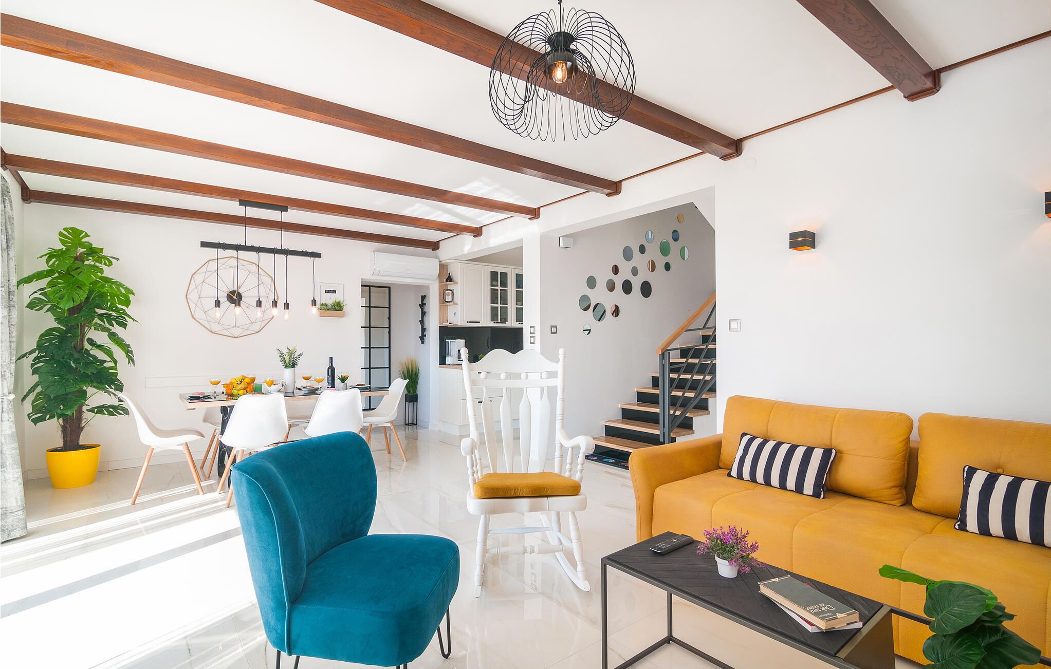 A modern living room with a sofa, chairs, a coffee table, and a staircase leading to another level.
