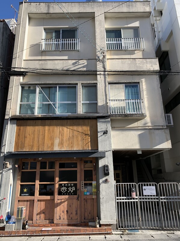 Un edificio de varios pisos con una tienda de madera en la planta baja llamada 'Sapporo Pollo'.