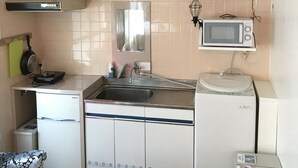 A compact kitchen with white cabinets, a stainless steel sink, a microwave, and a built-in oven. - Okinawa 13 (Naha)
