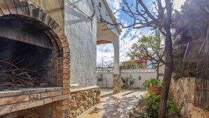 Un espace extérieur aménagé en patio, avec une cheminée en briques, des murs en pierre et des plantes en pot.